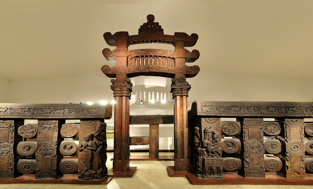 The red sandstone Bharhut gateway and carved railing medallions, reassembled in a museum gallery.