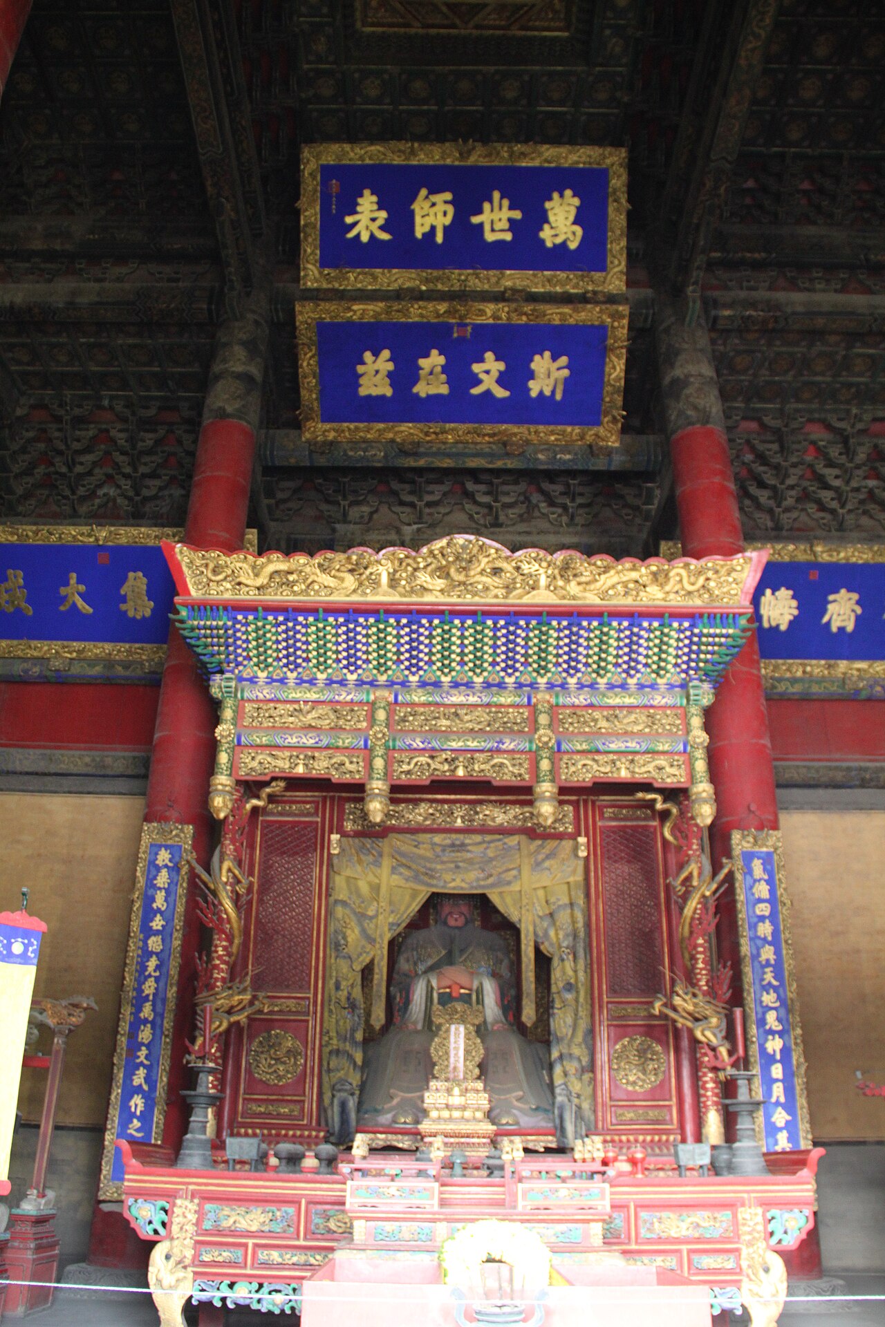 The shrine of Confucius in the Dacheng Hall at Qufu: the sage's tablet in its canopied altar beneath plaques honoring him as teacher of ten thousand generations.