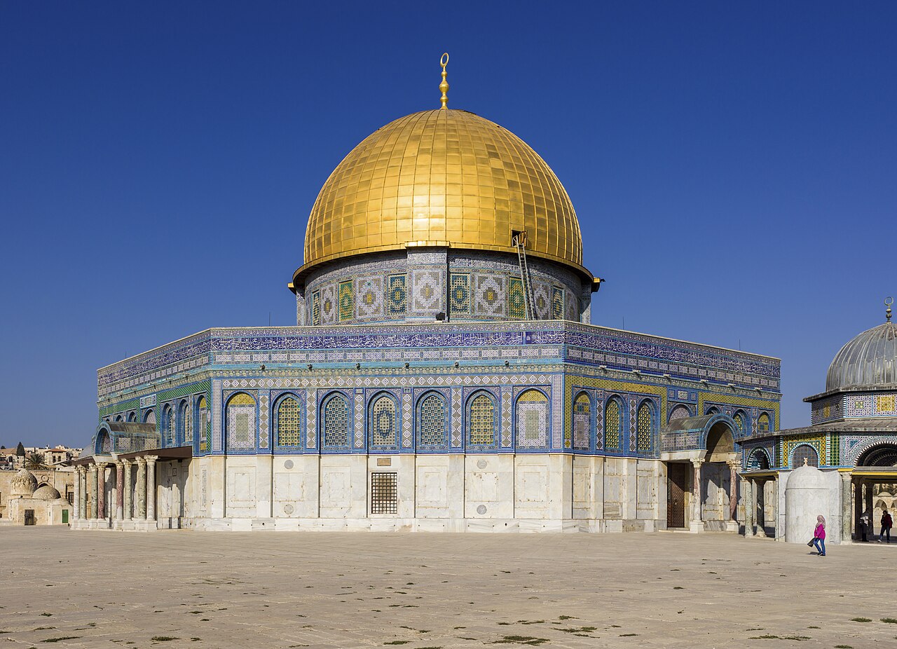 The Dome of the Rock in Jerusalem under a clear sky: gilded dome over an octagon of blue and turquoise tilework and marble.