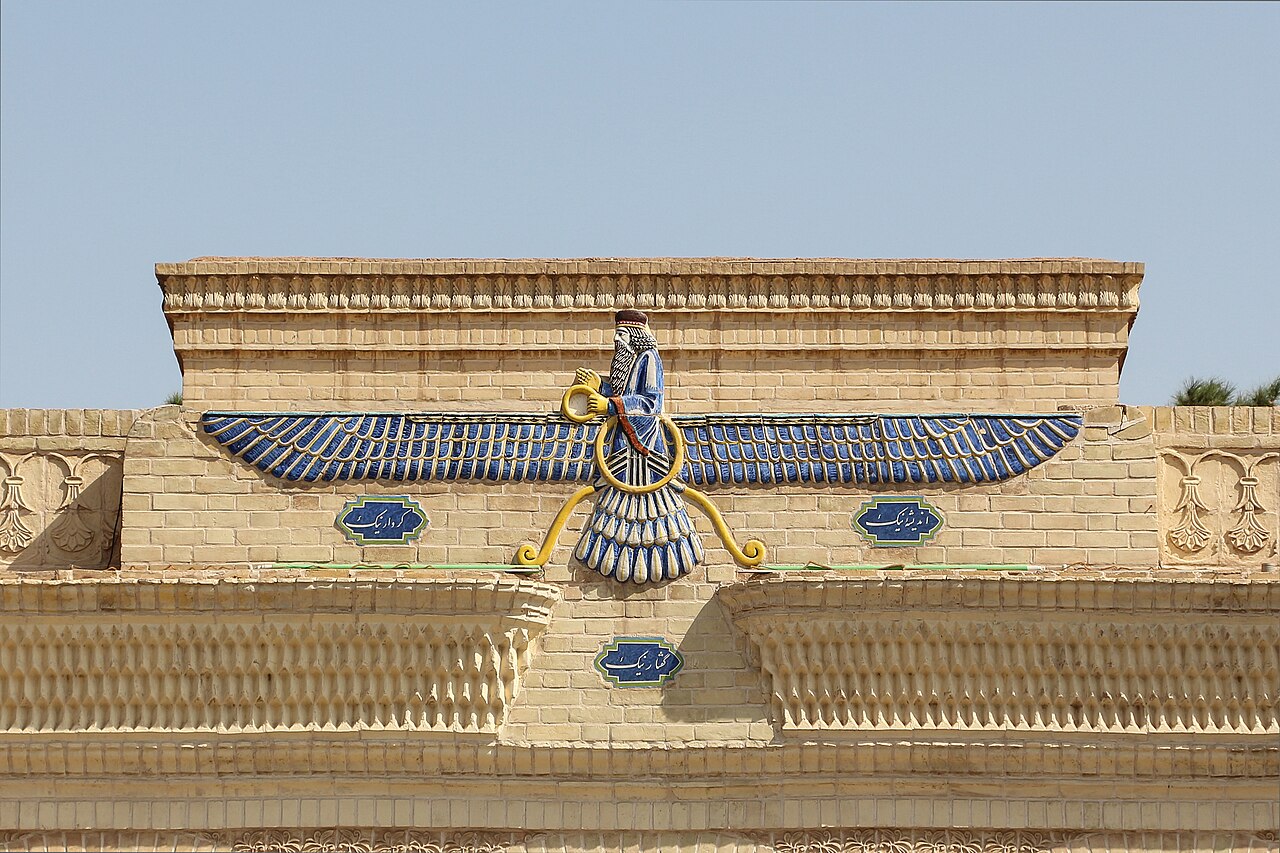 A vivid blue-and-gold fravahar, the winged human figure above a disc, adorns the brick facade of the Yazd fire temple.