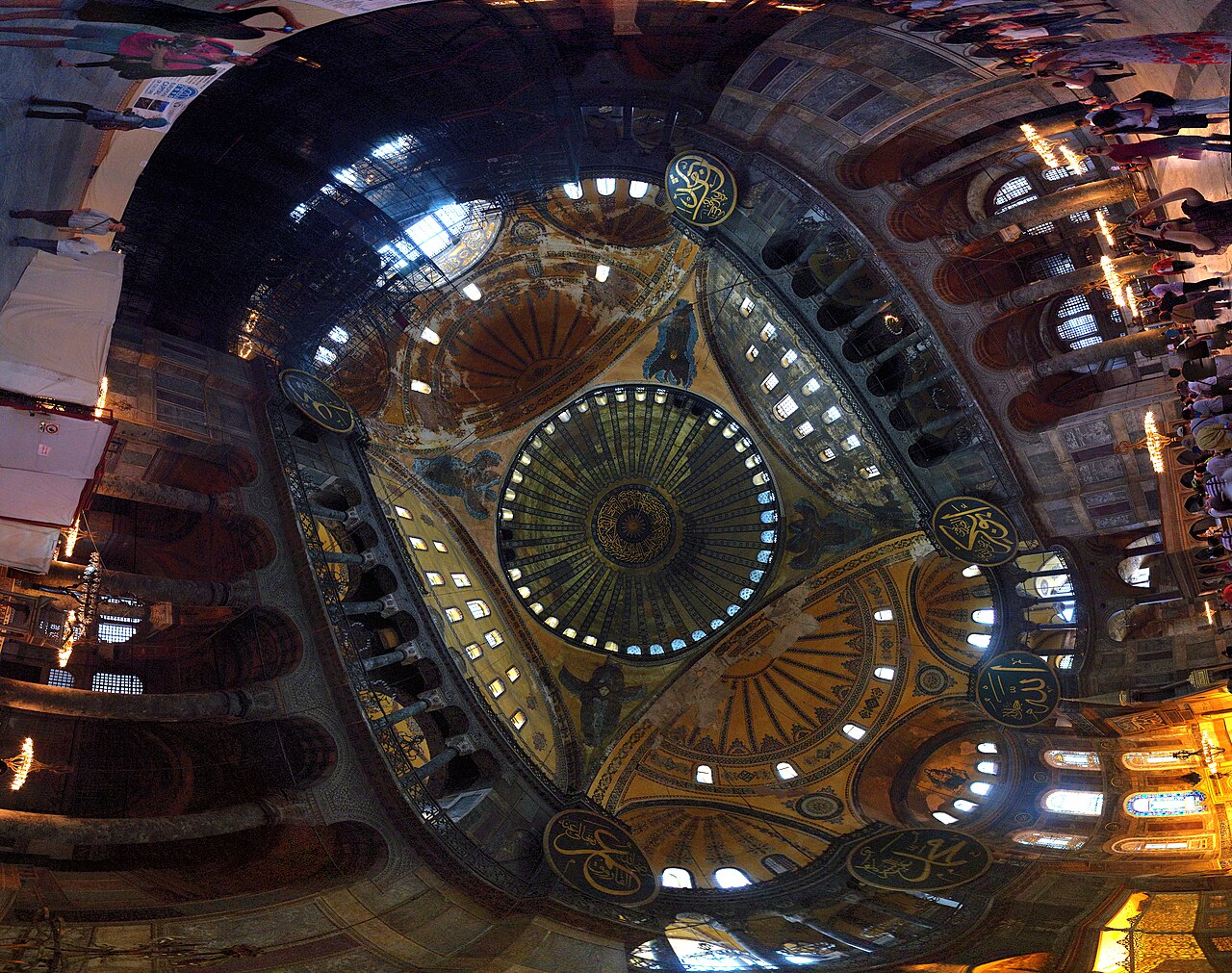A panoramic view up into Hagia Sophia's dome and semi-domes, ringed with windows, the seraphim and the great Ottoman calligraphic roundels visible.
