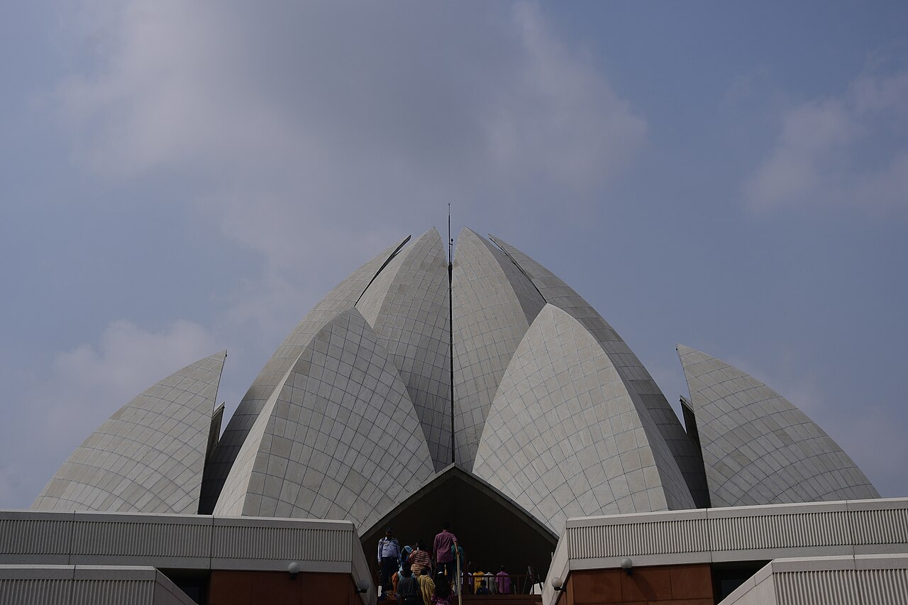 The white marble petals of New Delhi's Lotus Temple rise against the sky, seen from below at the entrance.