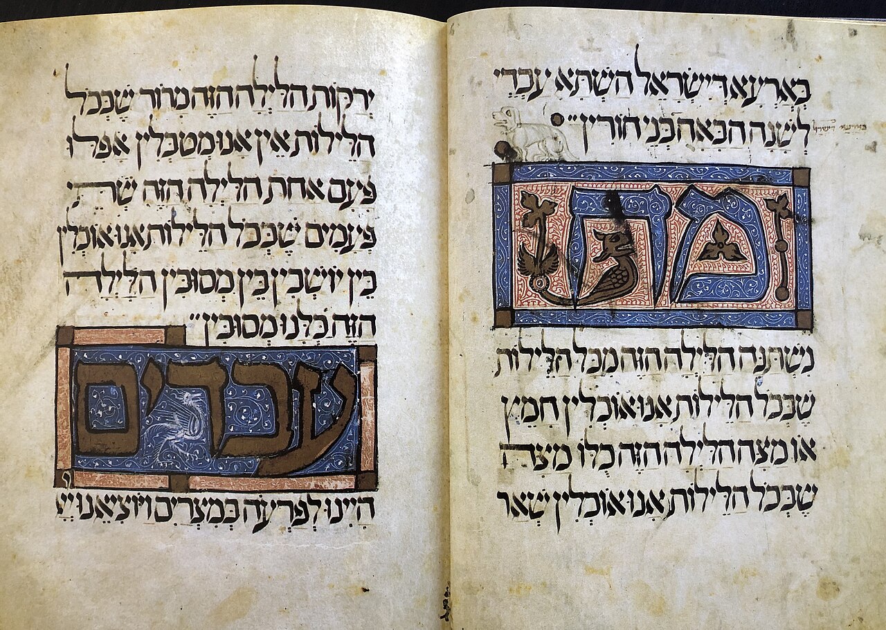 An open parchment spread of the Sarajevo Haggadah with Hebrew text and two illuminated initial-word panels in blue and gold.