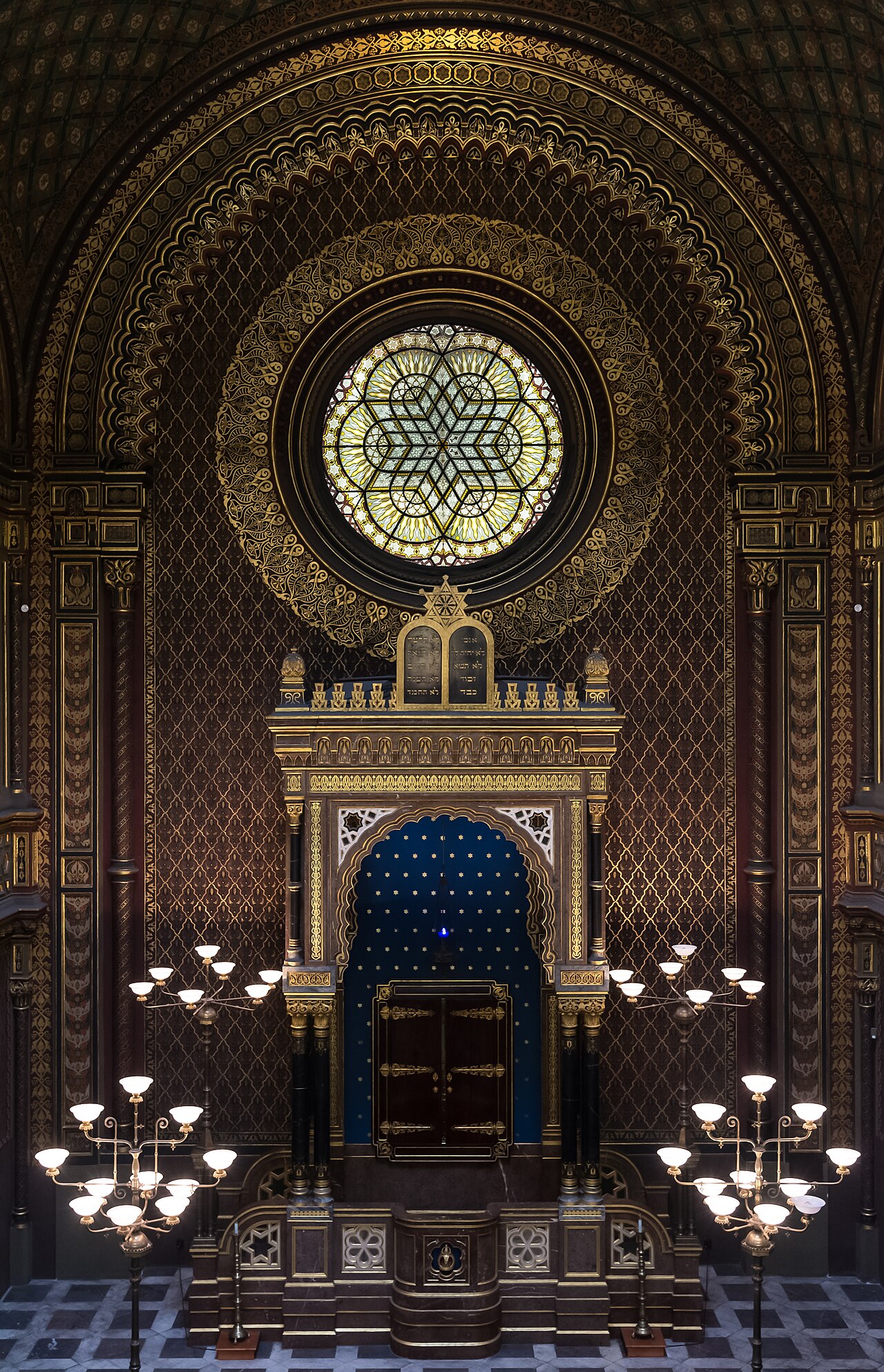 The gilded Moorish-revival Torah ark of Prague's Spanish Synagogue, tablets of the Law above its doors, beneath a large stained-glass rose window.