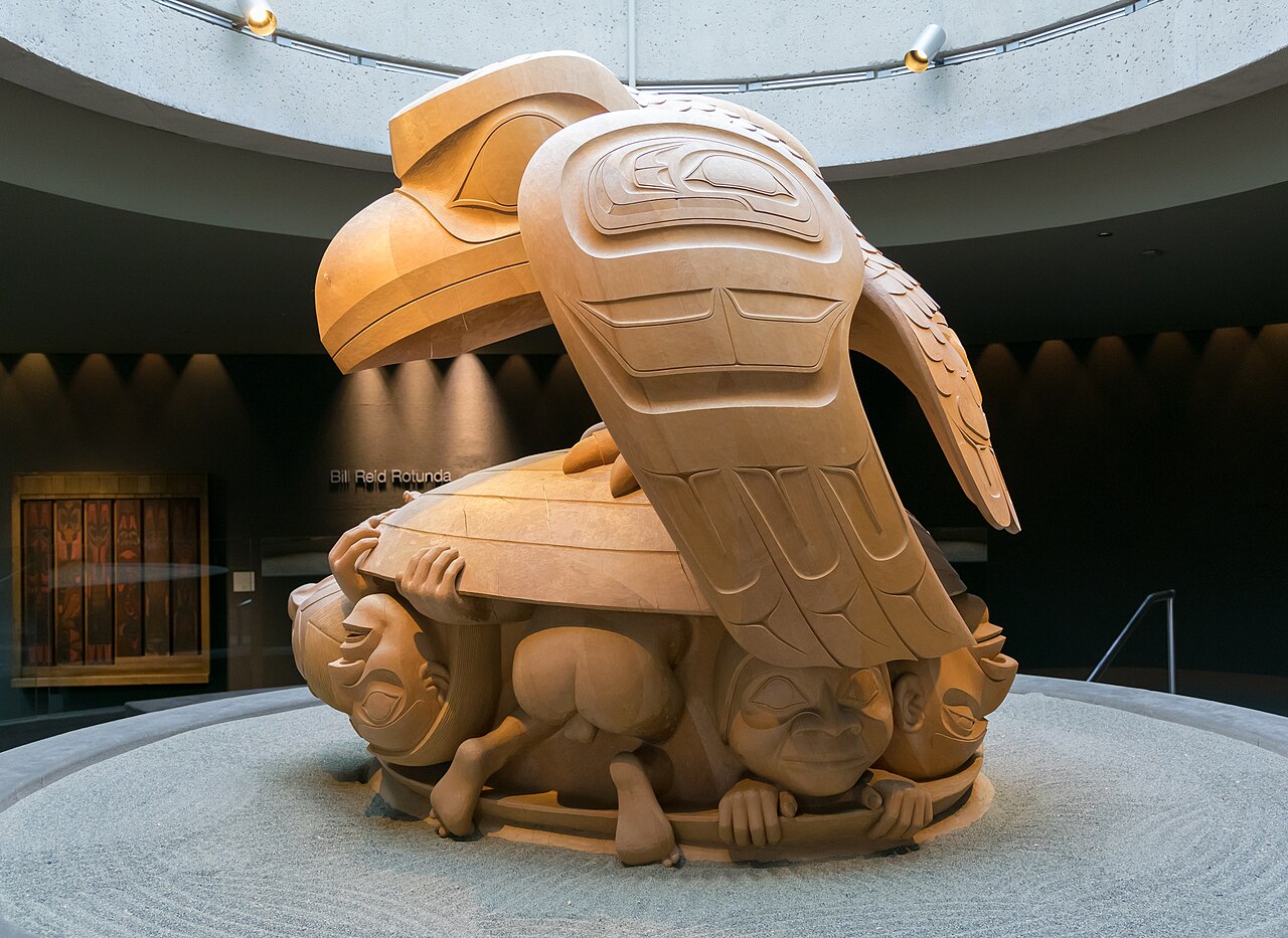 Bill Reid's monumental yellow-cedar sculpture The Raven and the First Men in its museum rotunda: the great Raven perched on a giant clamshell from which the first human beings are emerging.
