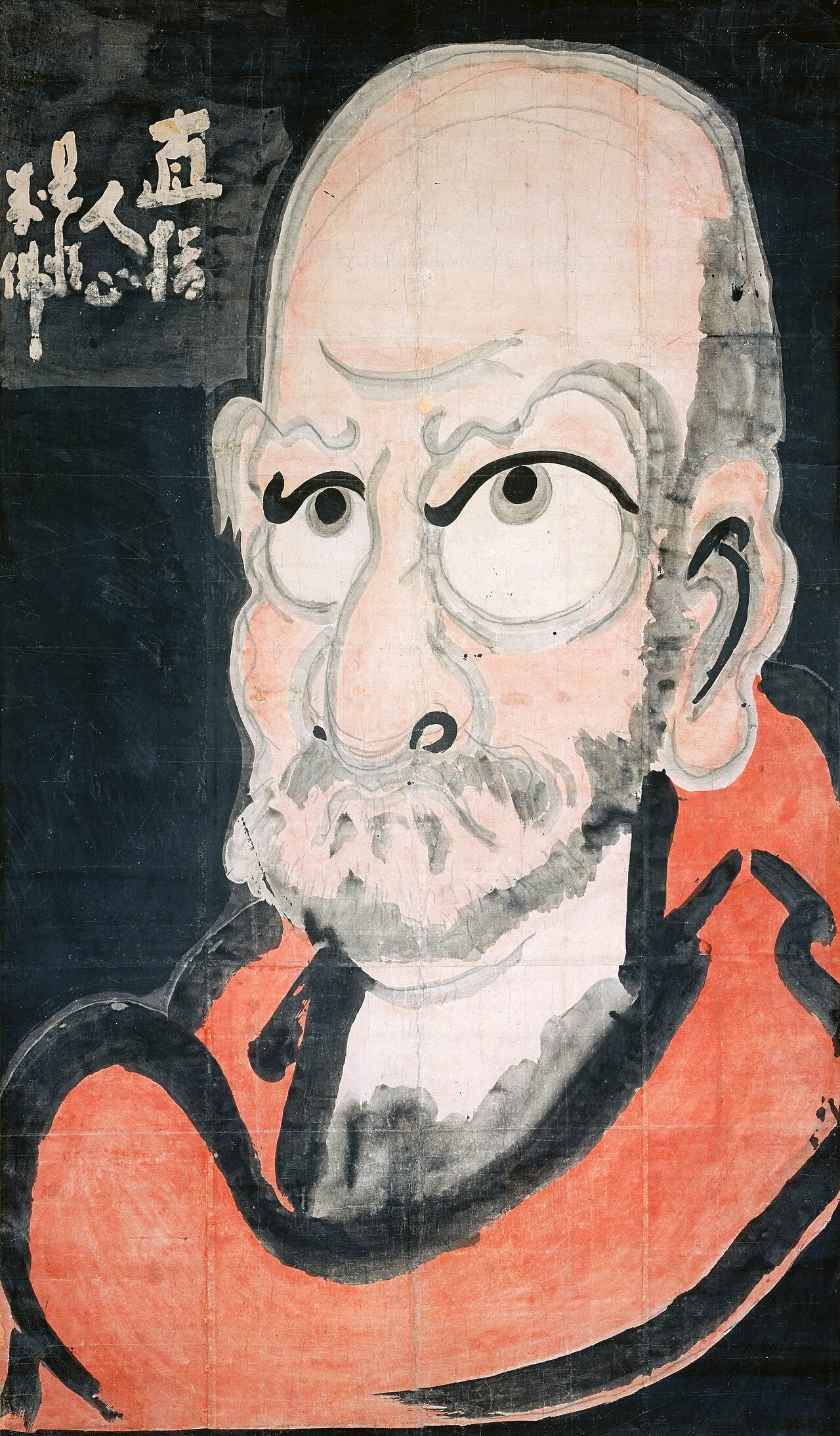 Hakuin Ekaku's monumental Daruma: the bald, wide-eyed, red-robed face of Bodhidharma painted in bold ink and color on a black ground, with white calligraphy at upper left.
