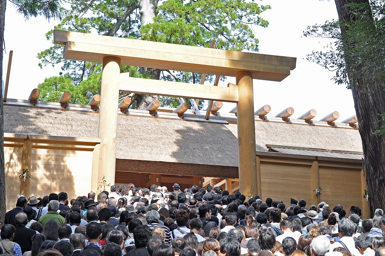 A crowd before the newly rebuilt Ise Grand Shrine at the 2013 shikinen sengu: a brand-new unlacquered hinoki torii and the fresh pale wood and thatched roof of the just-completed shrine building.
