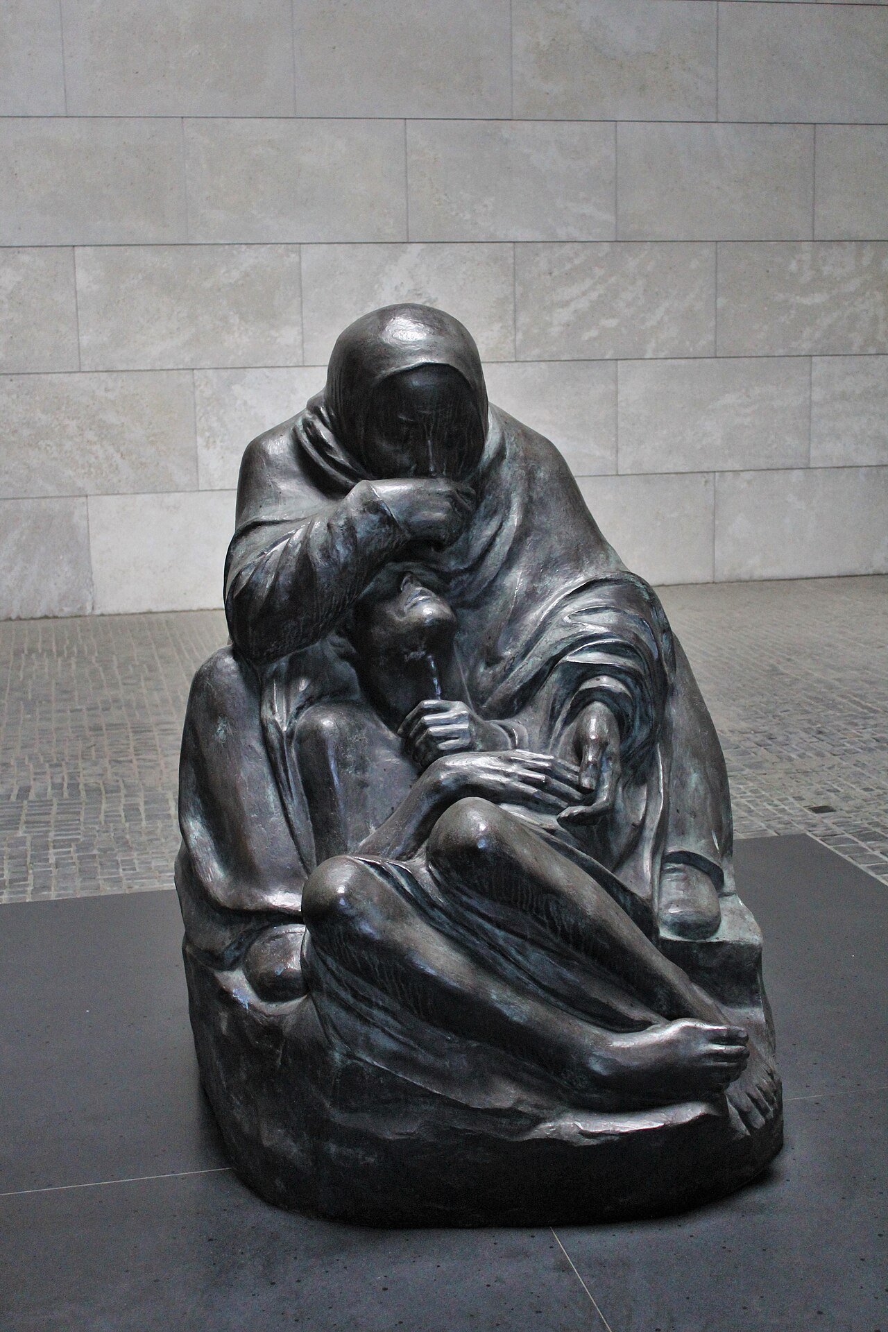 Käthe Kollwitz's bronze Pietà, Mother with her Dead Son, in Berlin's Neue Wache: a shrouded seated mother bowing over the body of her son stretched across her lap.