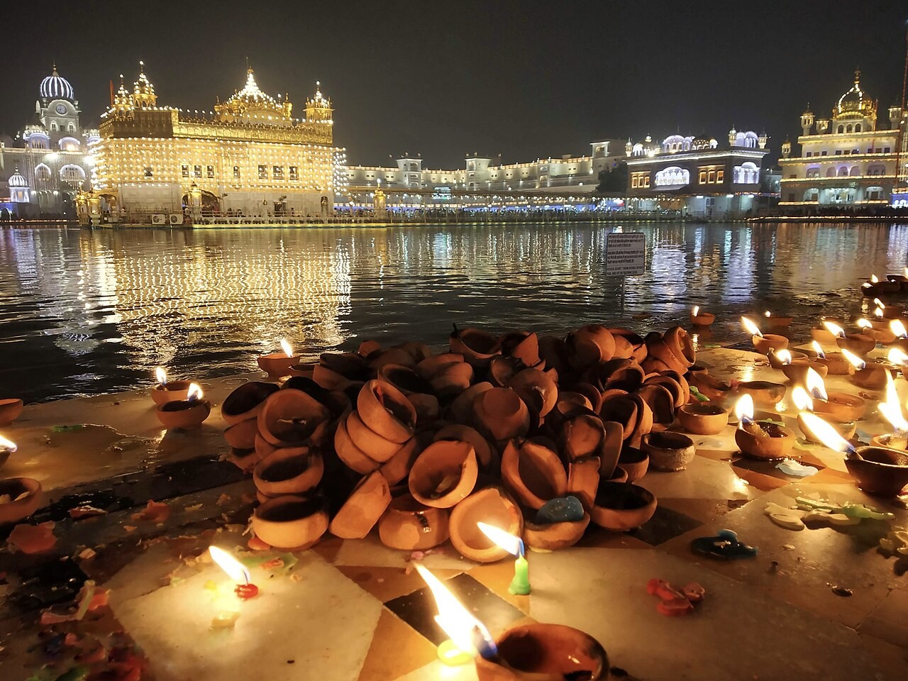 The Golden Temple illuminated at night, diyas burning along the sarovar.