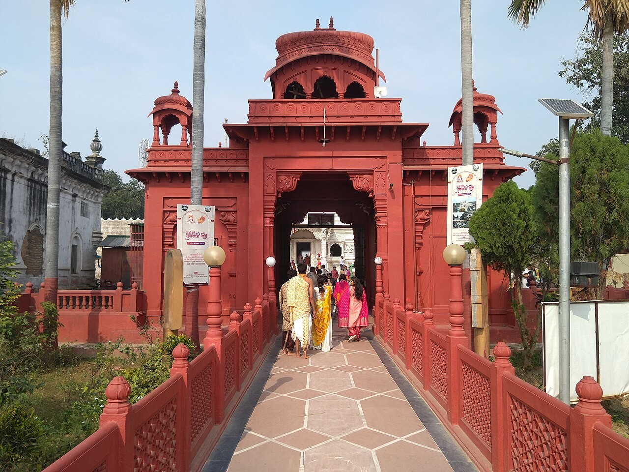 Pilgrims cross the causeway through the red gateway at Pavapuri, the white Jal Mandir standing in the lake beyond.