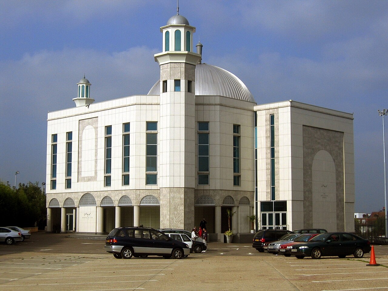 The Baitul Futuh Mosque in Morden, London, a large white Ahmadi mosque with a dome and a minaret, seen across its forecourt.