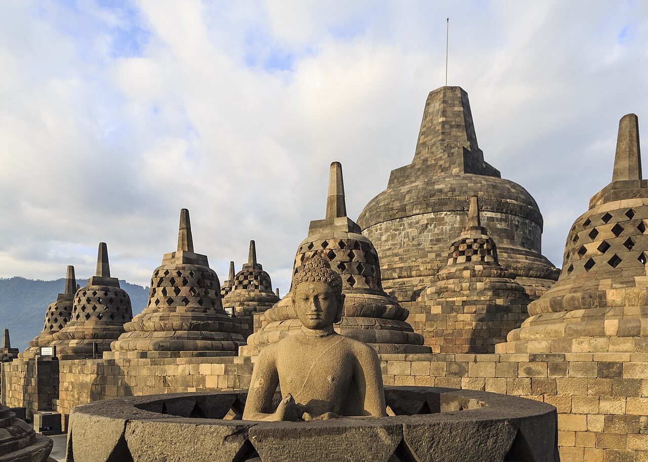 Weathered stone stupas and a seated Buddha statue at Borobudur, the great Buddhist temple in Java.