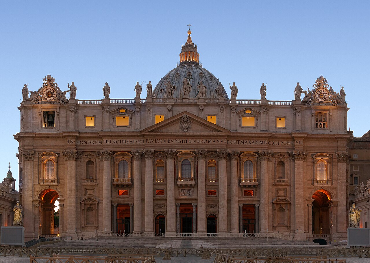 The facade of St Peter's Basilica in Vatican City at dusk, its windows lit.
