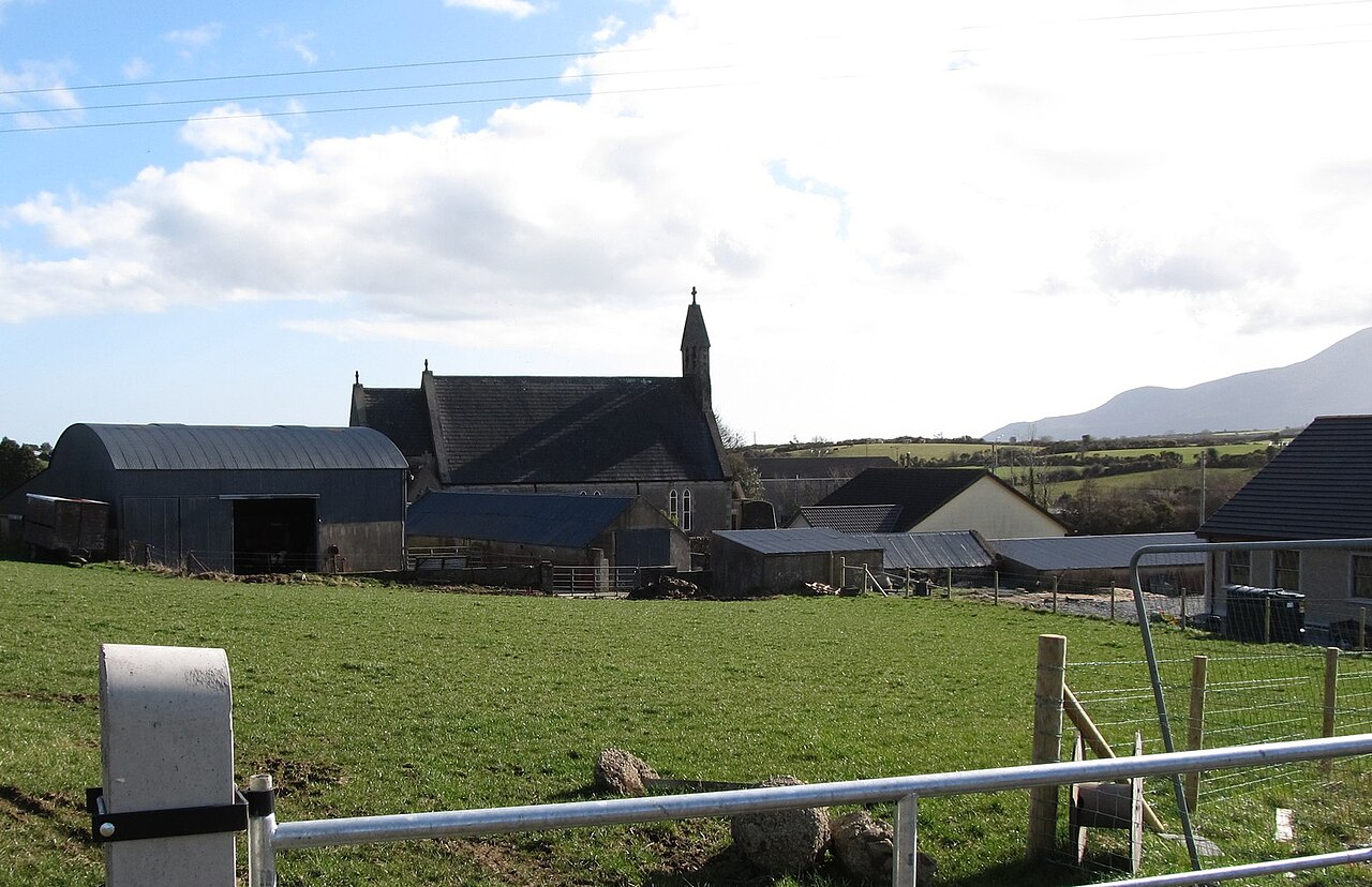 A small chapel among farm buildings in open countryside.