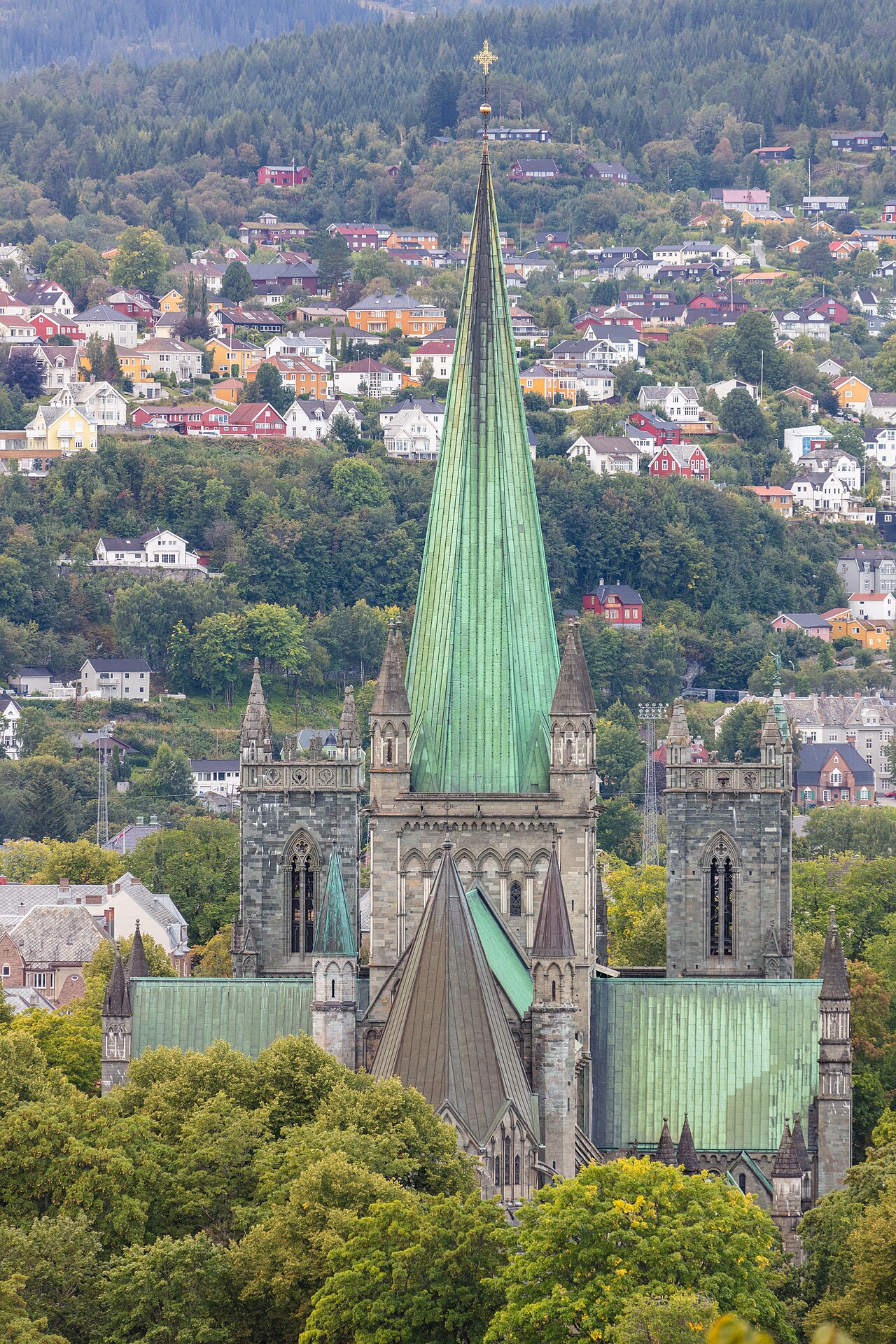The green copper spire and towers of Nidaros Cathedral rising over the trees of Trondheim.