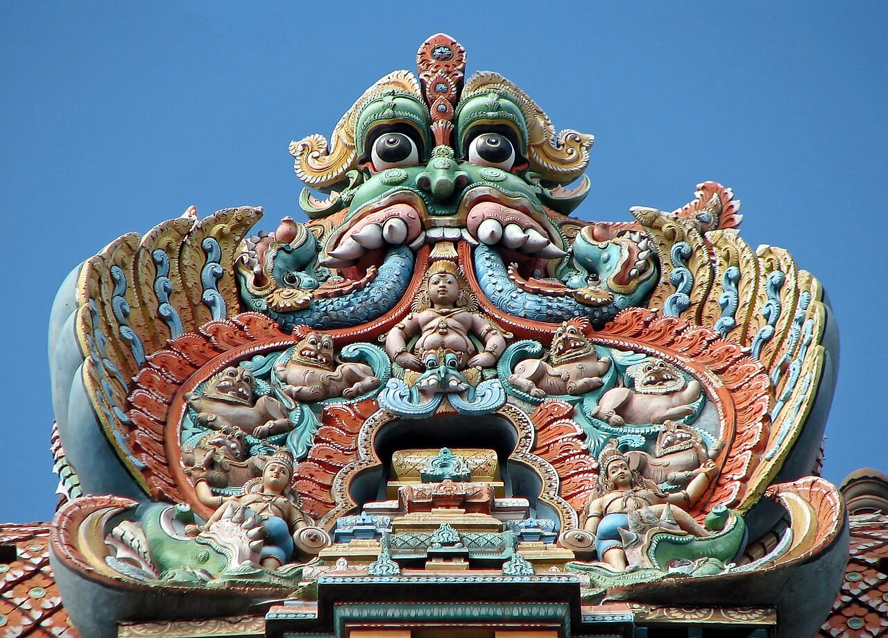 A close view of the painted sculpted figures covering a Madurai temple gopuram, crowded with Hindu deities.