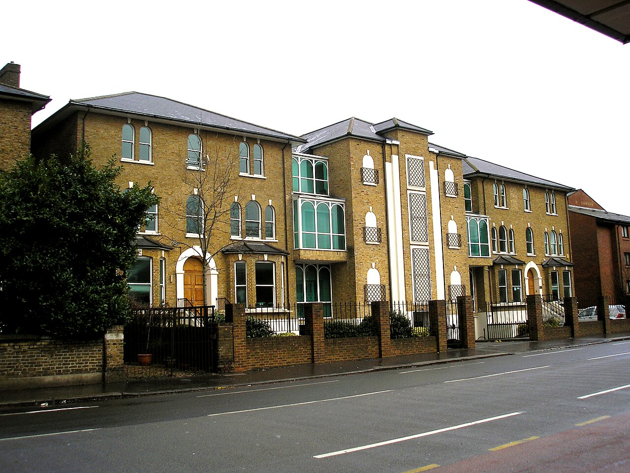 The Ismaili Jamatkhana in Croydon, South London, a brick building with arched windows and patterned screens, seen from across the street.