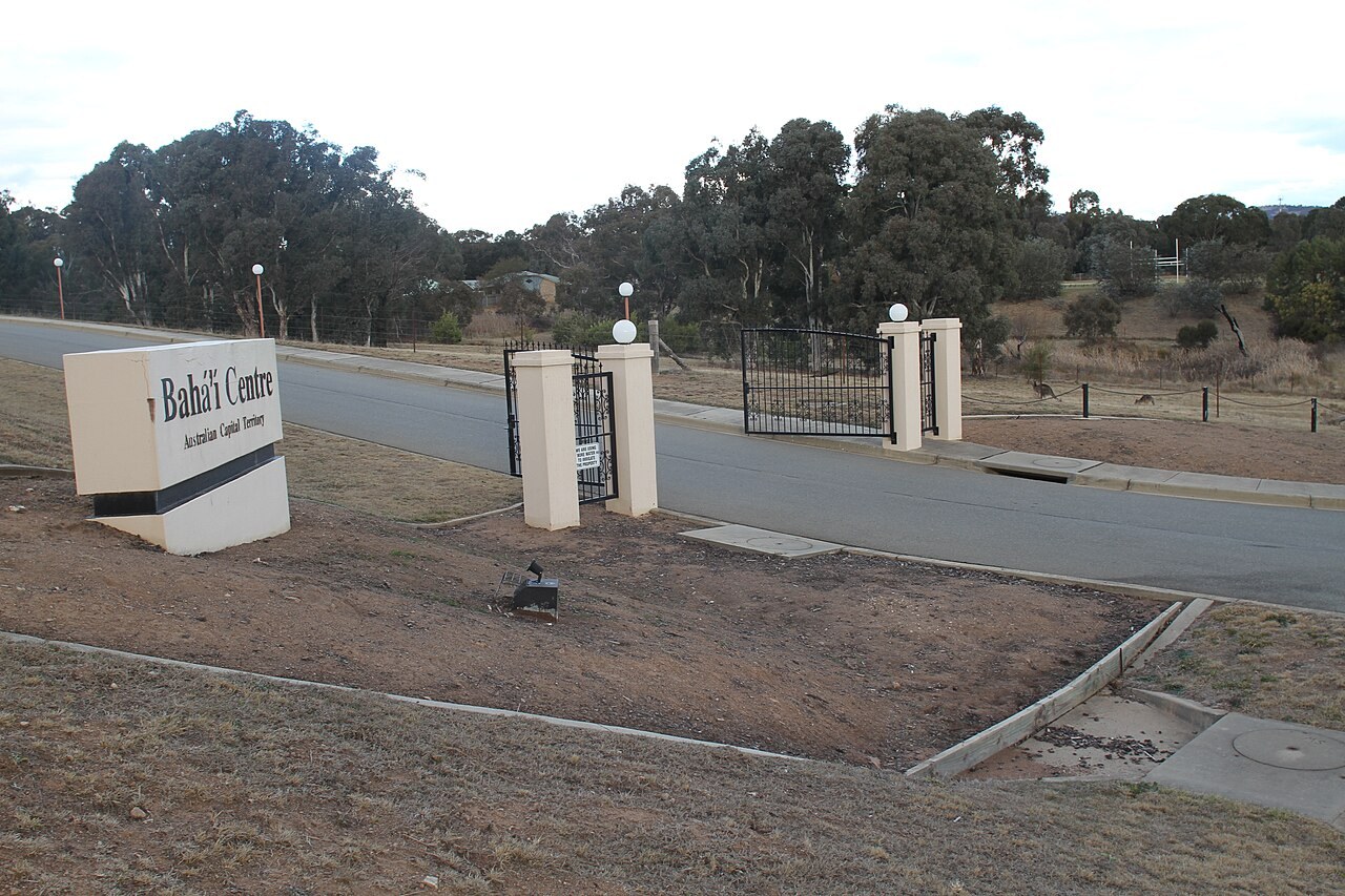 A roadside sign reading 'Bahá'í Centre' marks the entrance gate of the Canberra Bahá'í Centre.