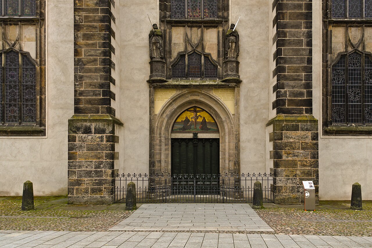 The door of the Castle Church in Wittenberg, framed by carved stone figures.