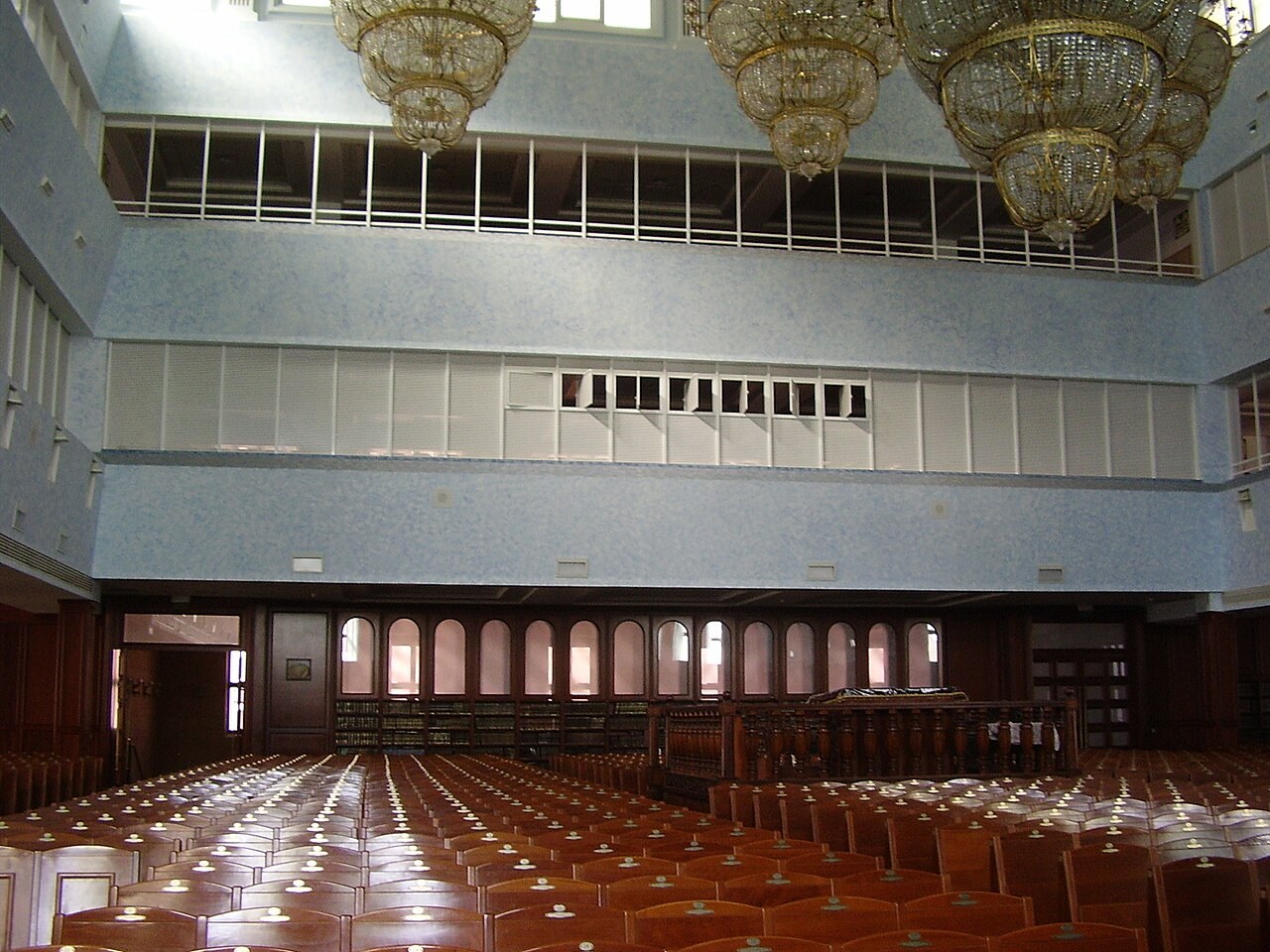 Rows of wooden seats face the ark inside the vast balconied sanctuary of the Great Belz Synagogue in Jerusalem.