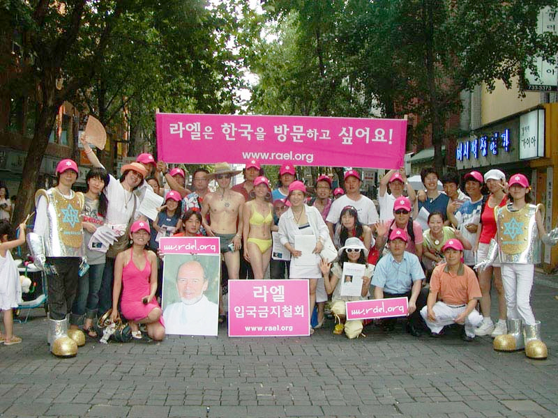 A gathering of Raëlians in South Korea, holding banners for the movement and a portrait of its founder, Raël.