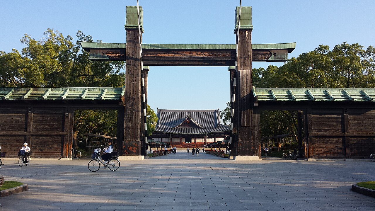 The great wooden gate of Tenrikyo Church Headquarters in Tenri, Japan, with the main sanctuary beyond a broad paved plaza.