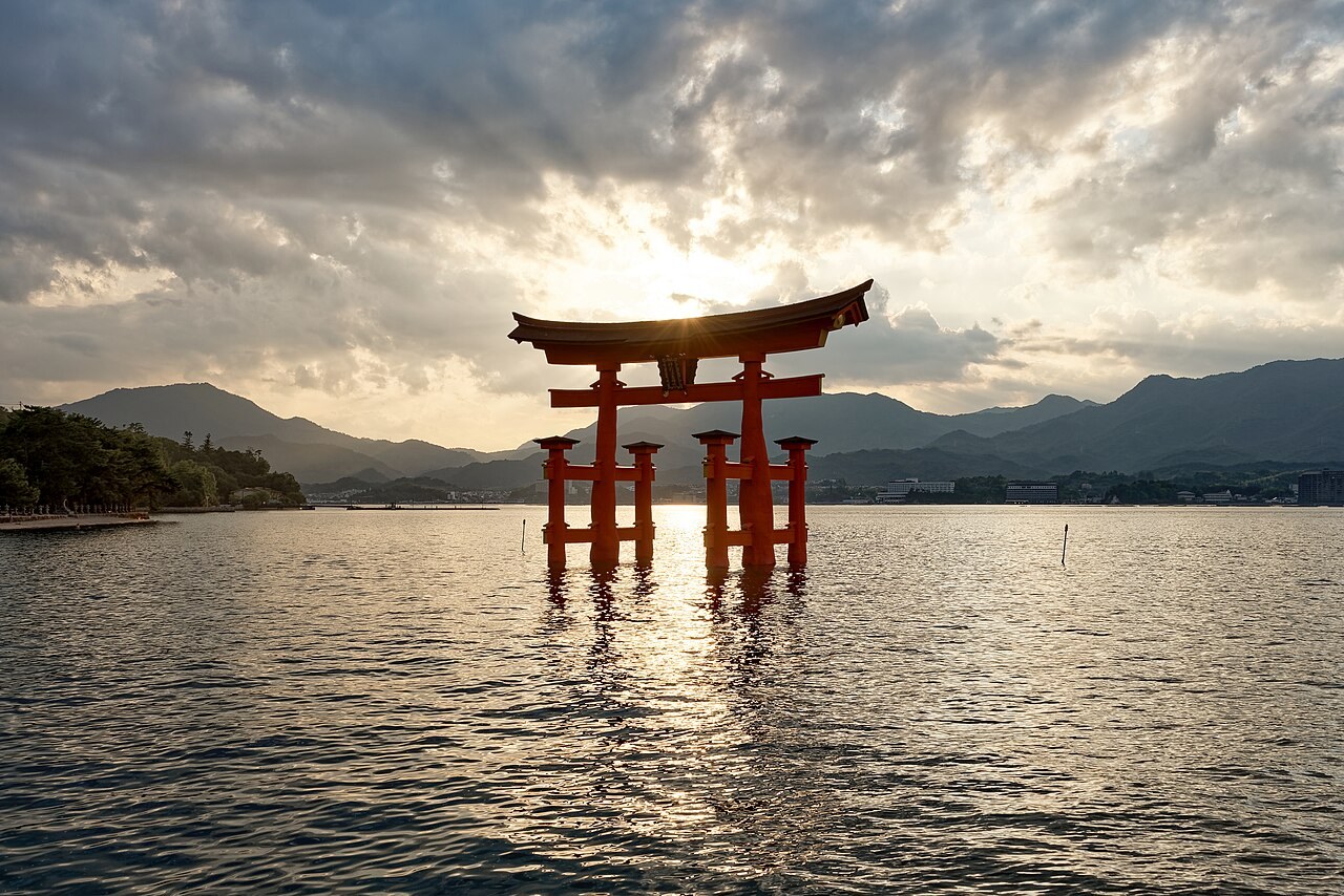 The great red torii of Itsukushima Shrine stands in the sea at sunset.