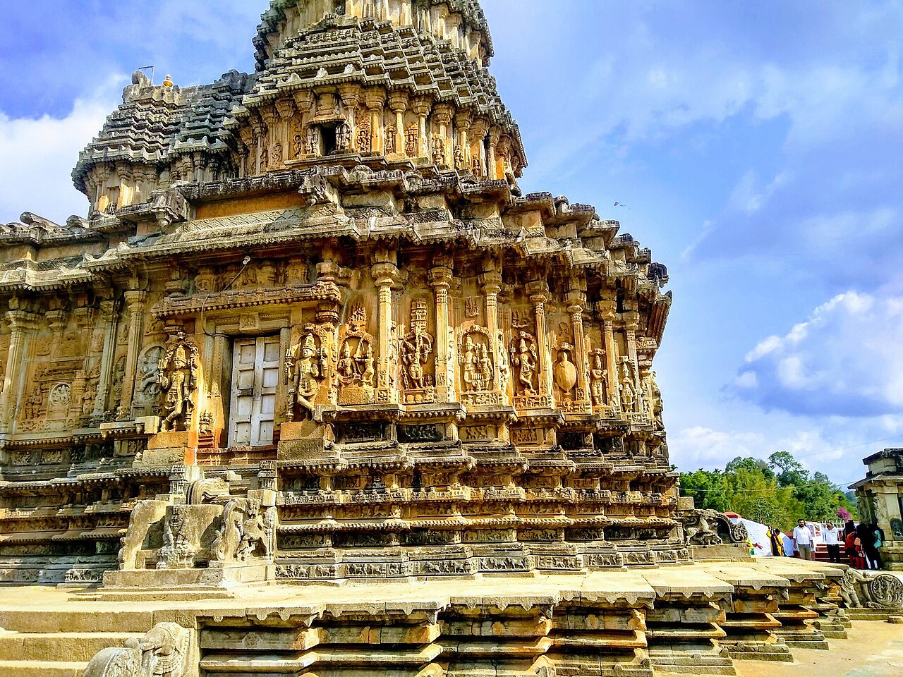 The ornate stone Vidyashankara Temple at Sringeri, covered in carved figures, stands under a blue sky.