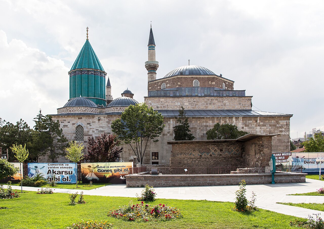 The Mevlana Museum in Konya, Turkey, the former Mevlevi Sufi lodge, with its green conical tomb tower, stone domes, and minaret.
