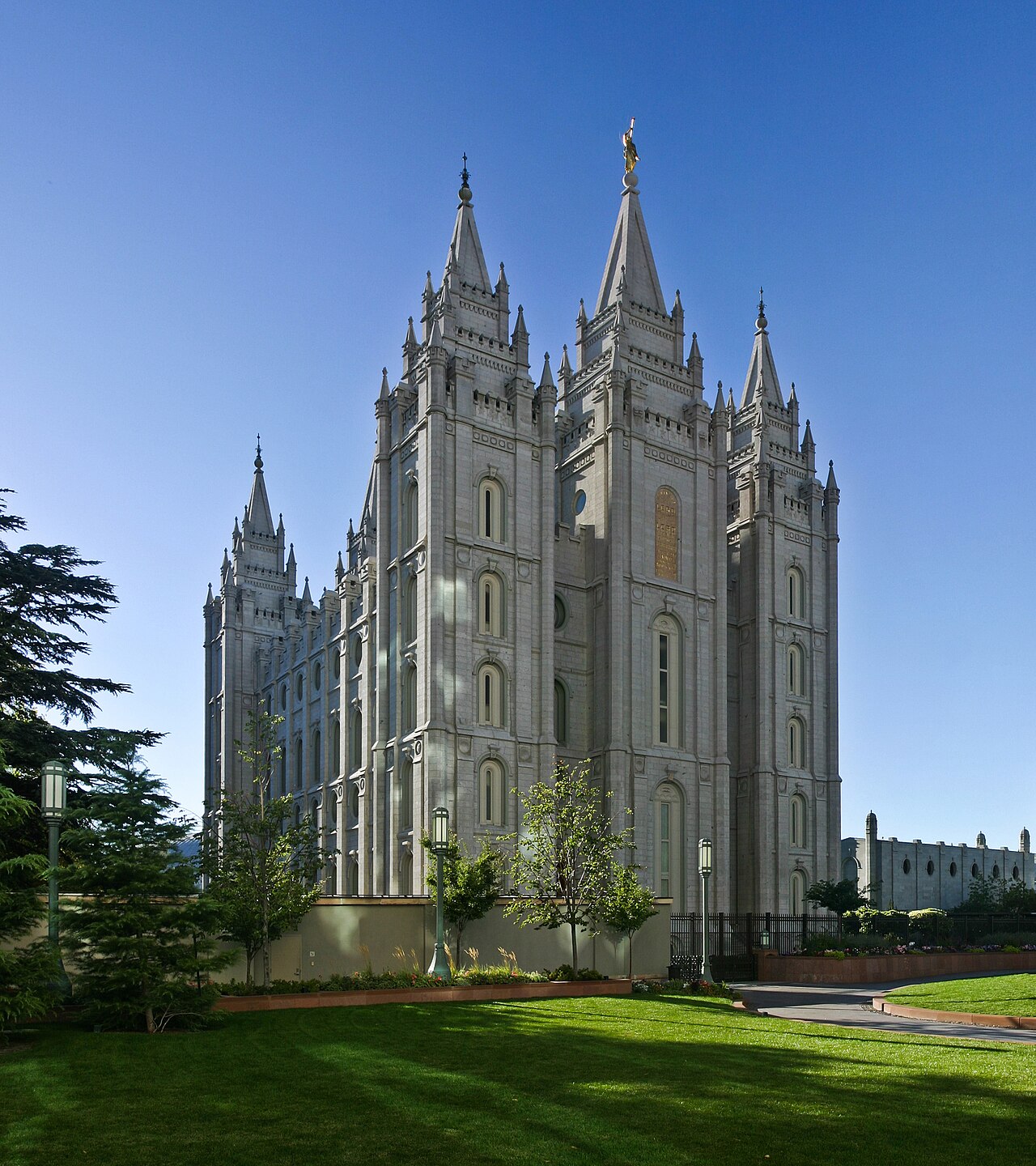 The grey granite spires of the Salt Lake Temple above green lawns in Salt Lake City.