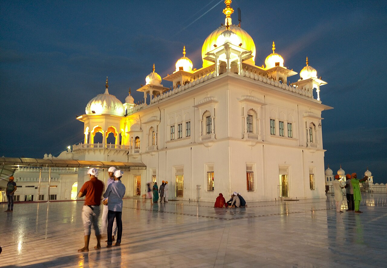 Takht Sri Kesgarh Sahib in Anandpur Sahib at night, the white gurdwara with golden domes lit against a dark sky.