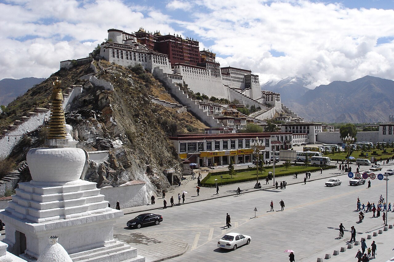 The Potala Palace crowns its hill above Lhasa, with a white chorten in the foreground.