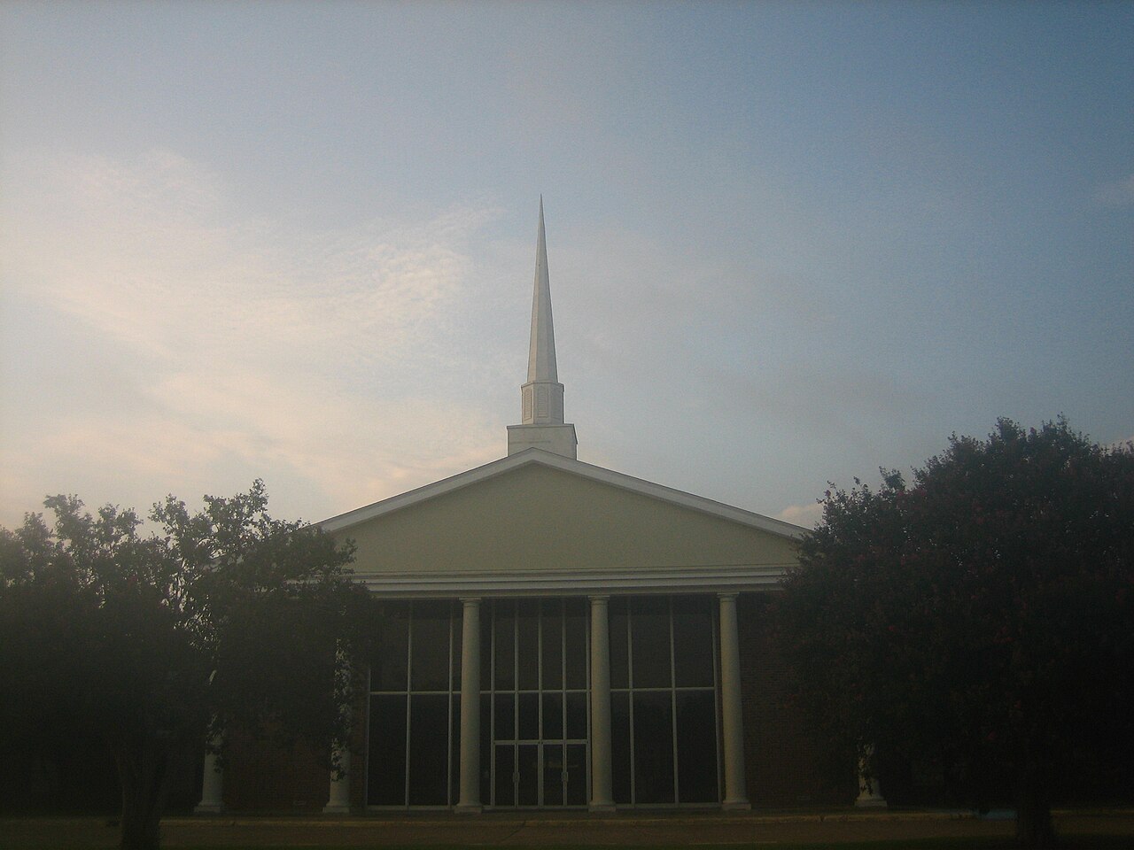 A white-steepled Pentecostal church in Alexandria, Louisiana, its glass front at dawn.