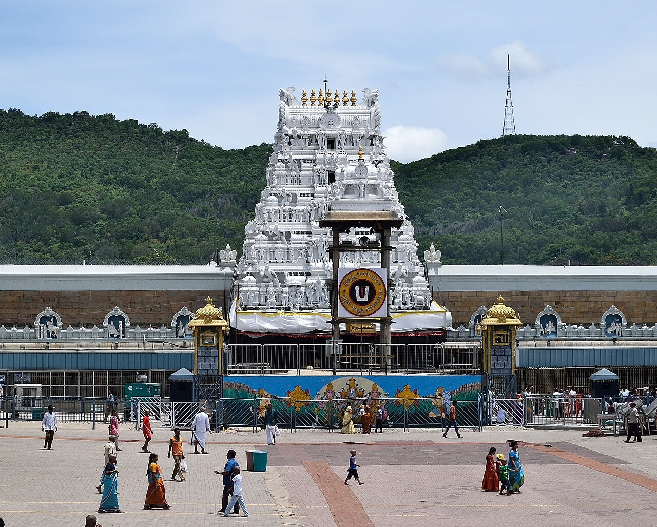 Pilgrims cross the plaza before the white gopuram of the Venkateswara Temple entrance at Tirumala.