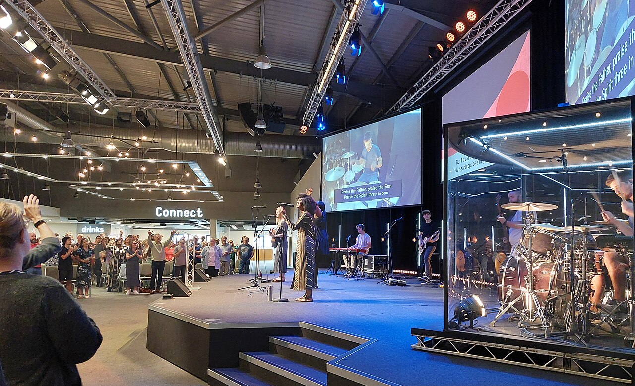 A worship band leading a congregation at Trent Vineyard church, singers and drums on a stage.