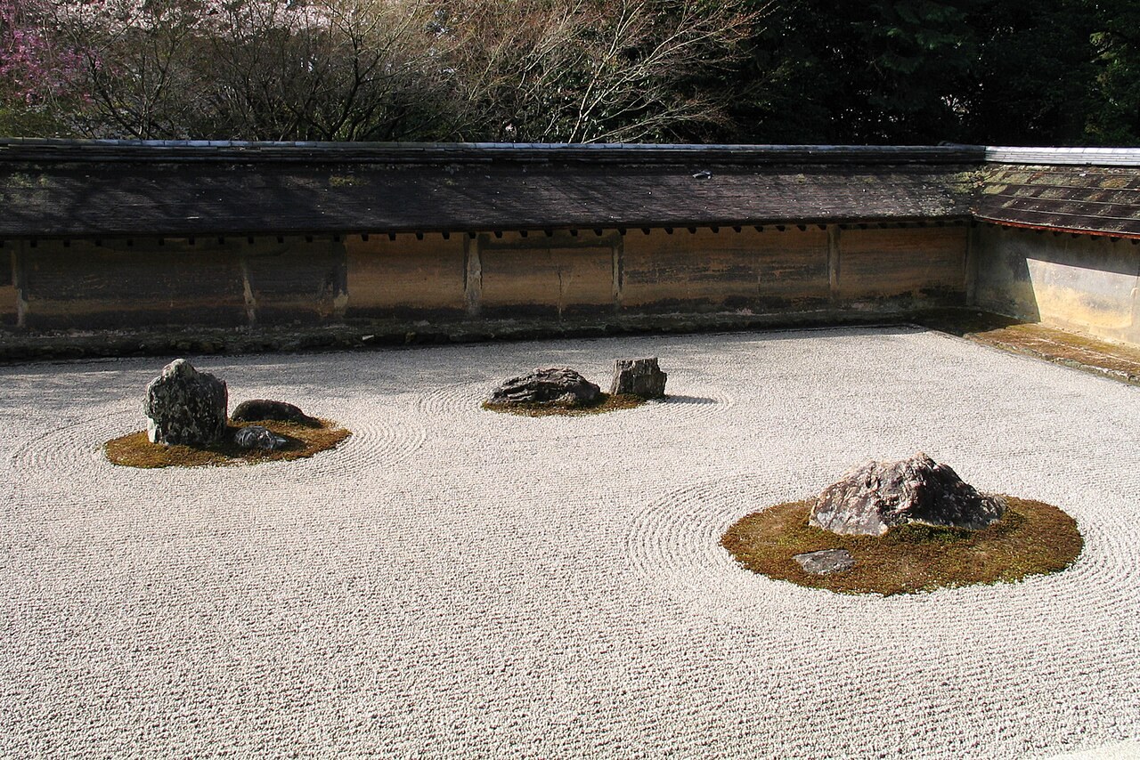 Rocks rest in raked white gravel inside the earthen walls of Ryoan-ji's dry garden in Kyoto.