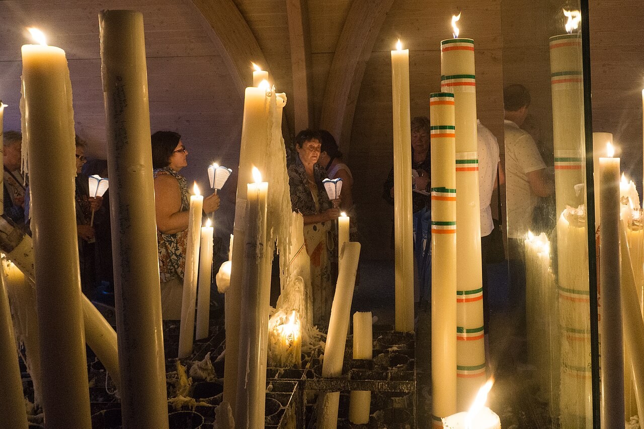 Pilgrims holding candles at the Sanctuary of Our Lady of Lourdes in France.