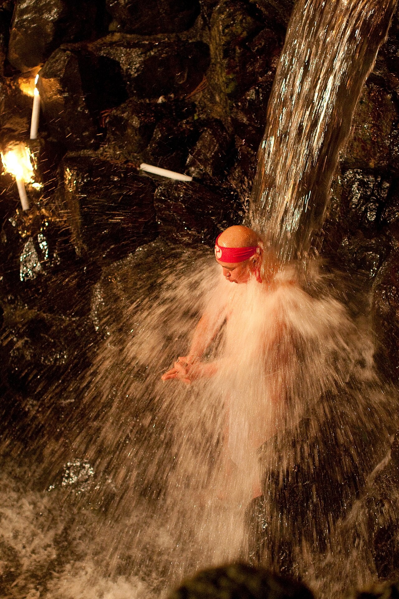 A practitioner standing under a waterfall in misogi, purification by cold water.
