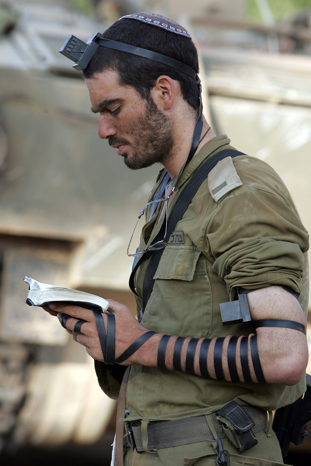 An Israeli soldier putting on tefillin, the leather boxes bound to arm and head.