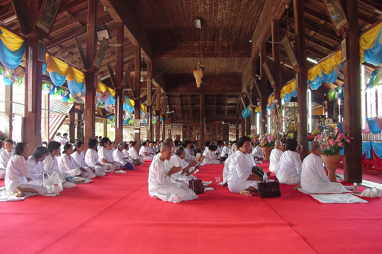 Buddhist devotees praying with folded hands before a Buddha image.