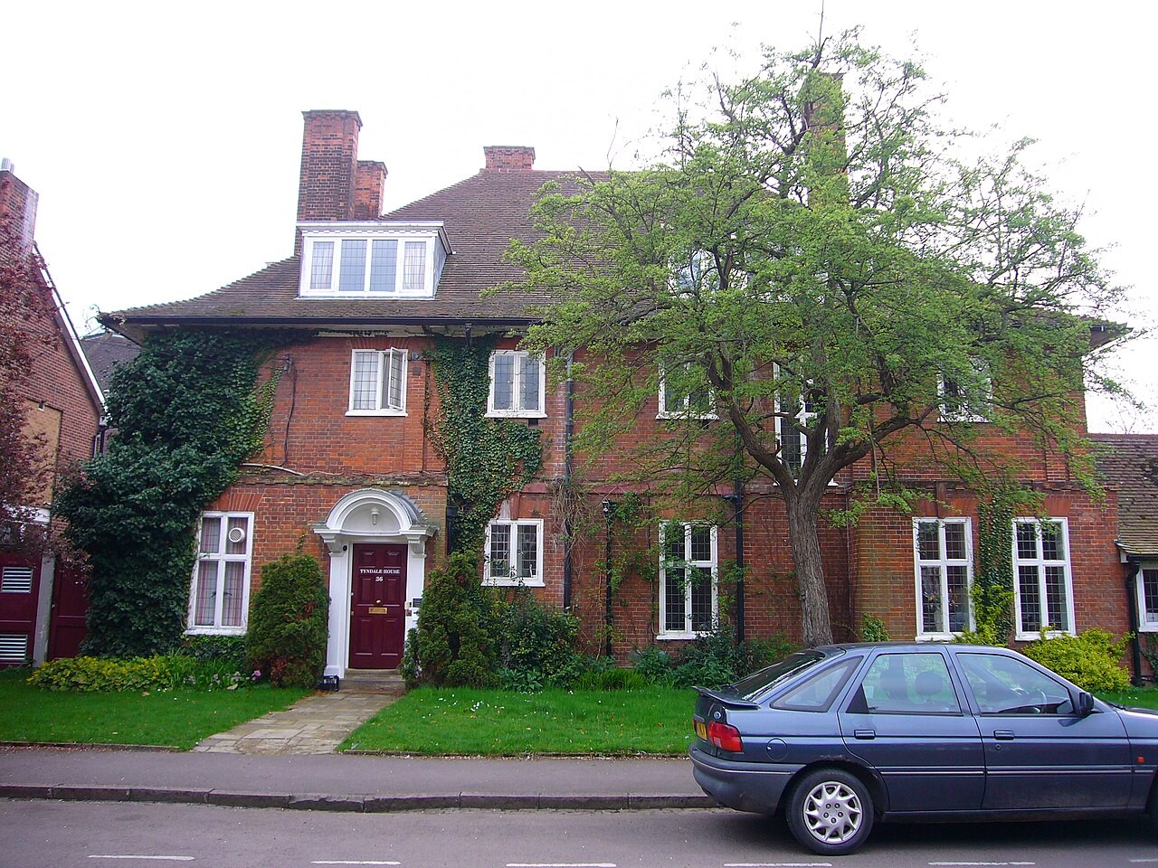Tyndale House in Cambridge, a large ivy-covered brick house behind a hedge, home of the biblical studies library that produces the STEP Bible.