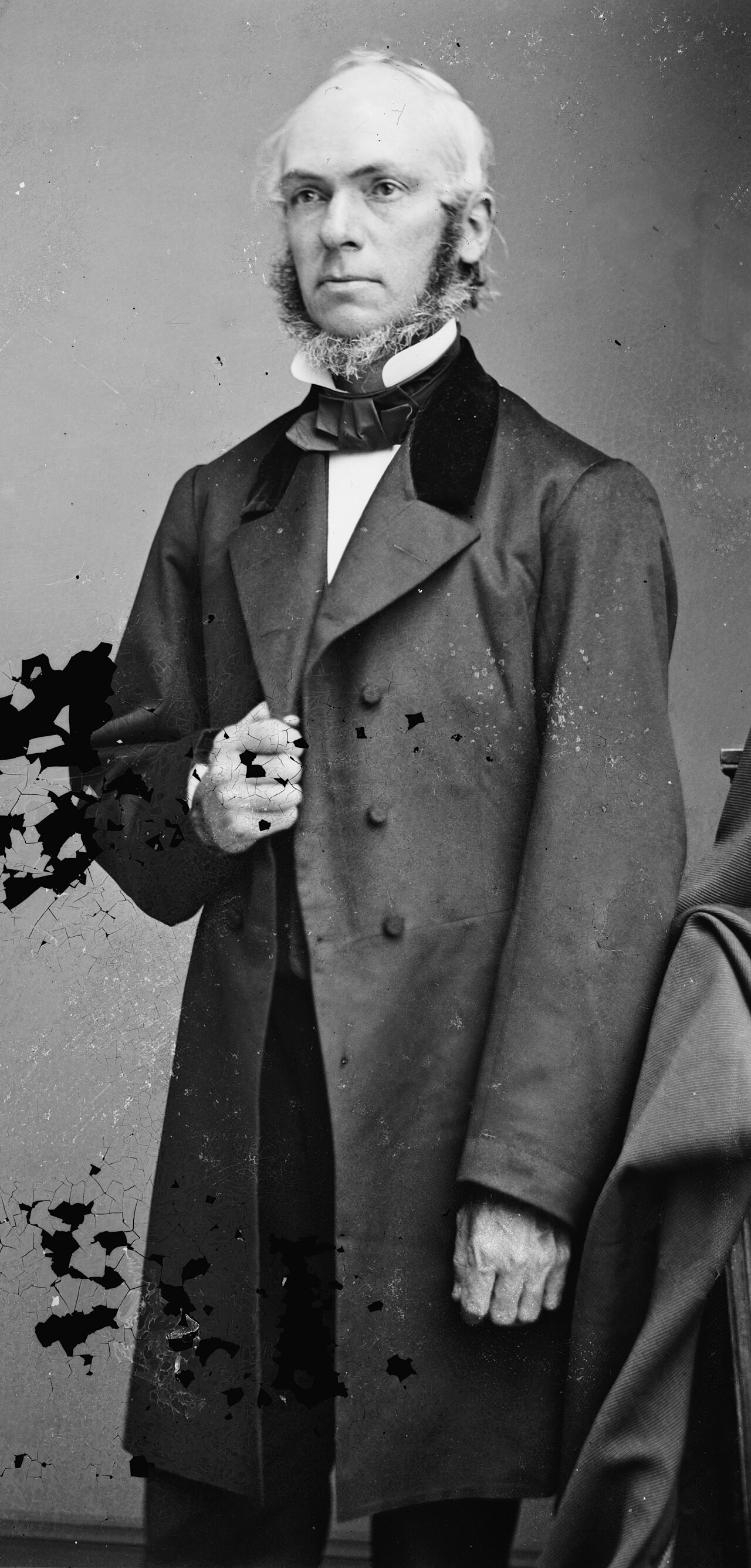 A full-length studio photograph of James Strong, an elderly white-haired man in a long dark coat holding a cane, from the Brady-Handy collection.