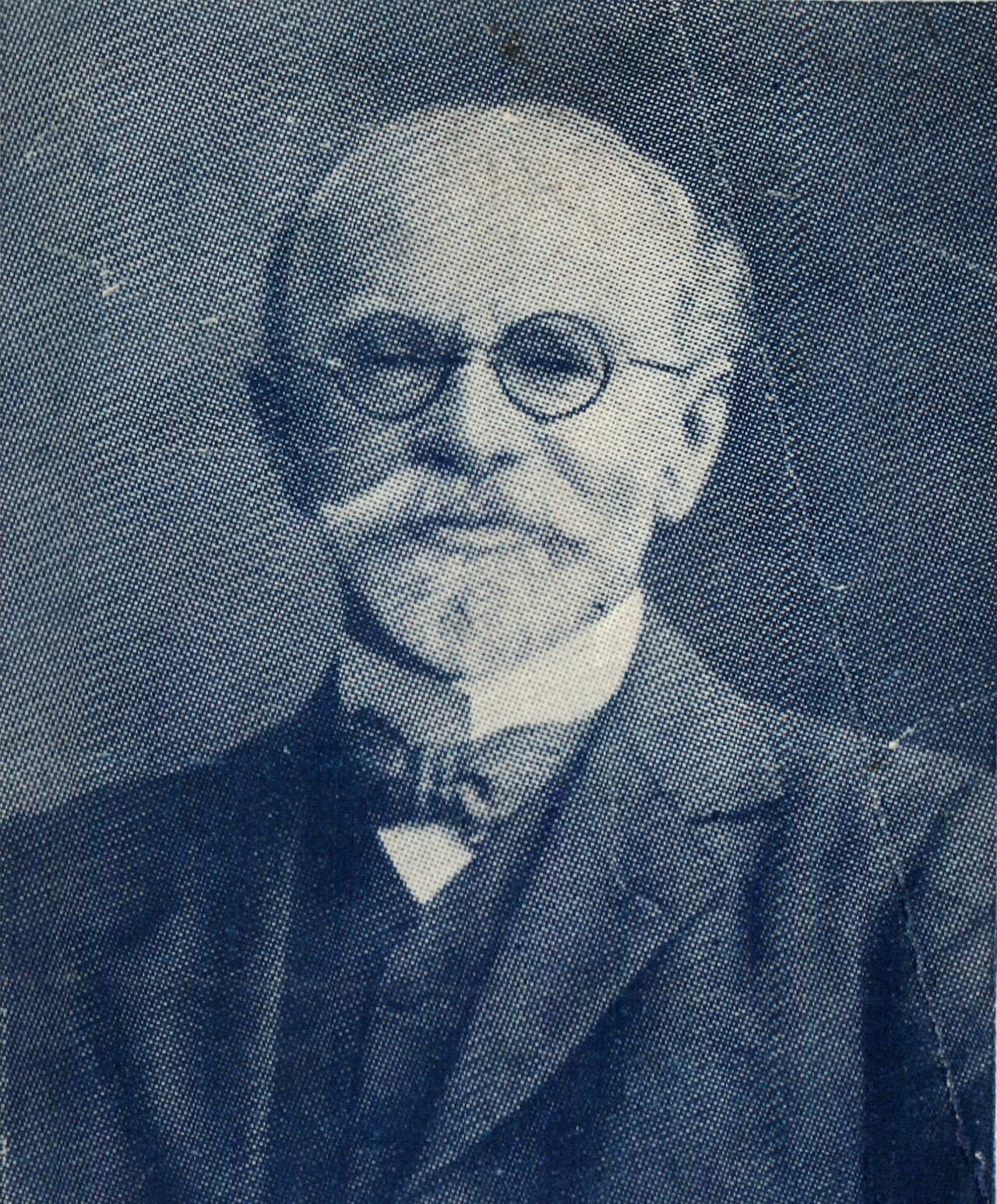 A blue halftone portrait of W. E. Vine in old age, a bald, white-bearded man with round glasses wearing a suit and bow tie.