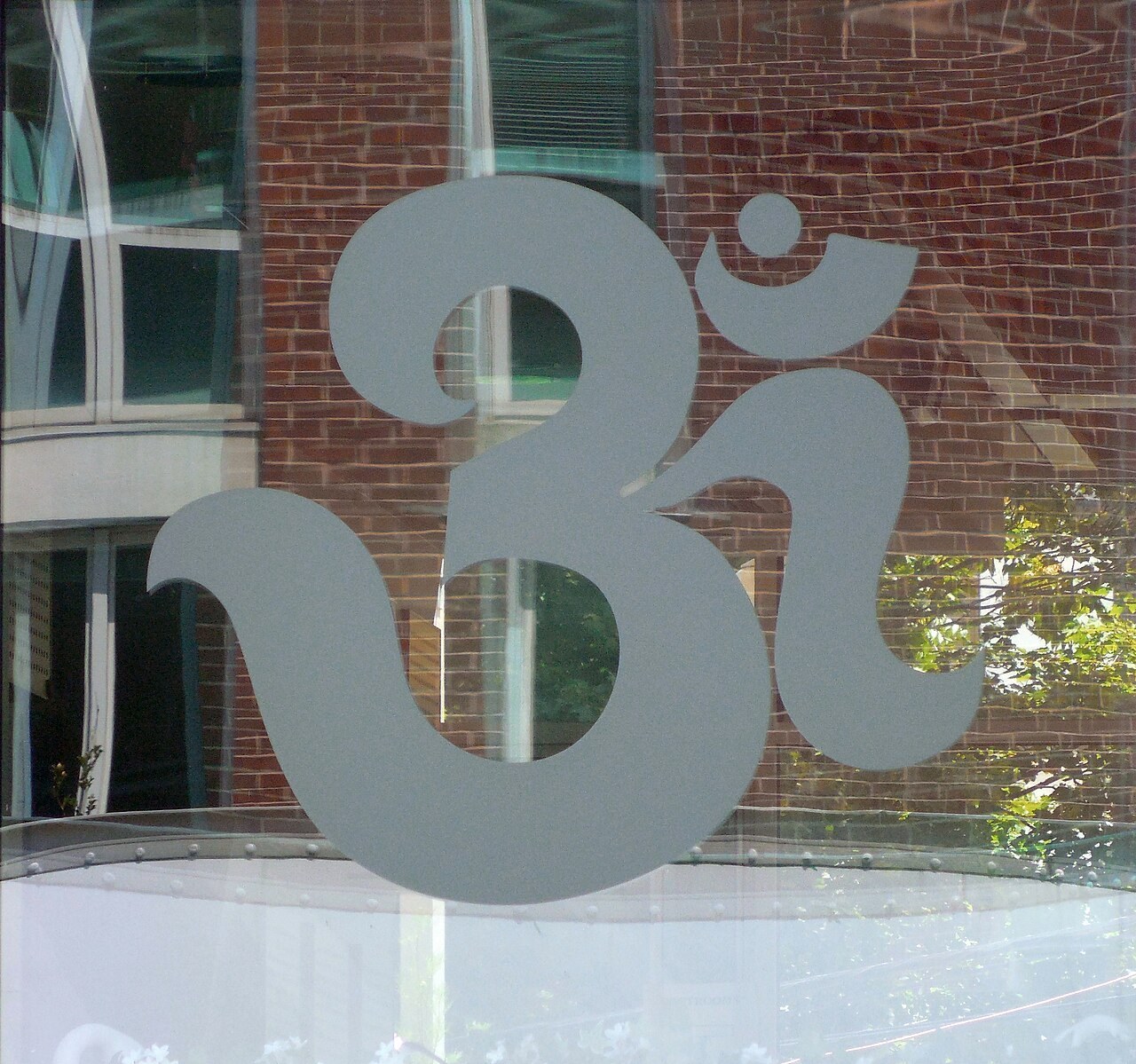 A large Om sign in frosted glass on the window of a temple, filling the whole frame.