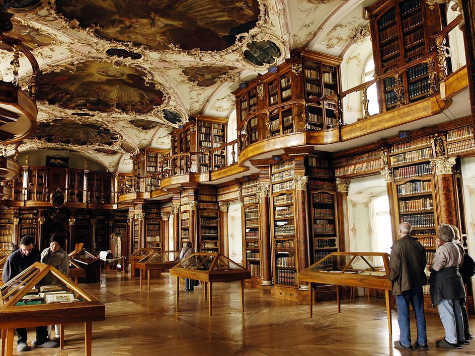 The rococo Baroque hall of the Abbey Library of St Gall in Switzerland, lined with wooden bookcases and globes.