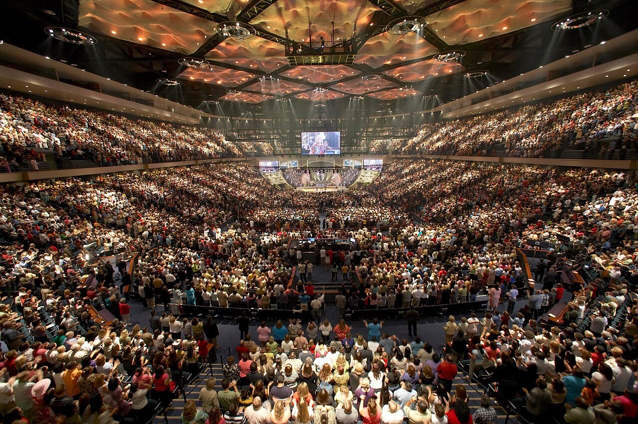 A vast congregation filling Lakewood Church's arena during a worship service.