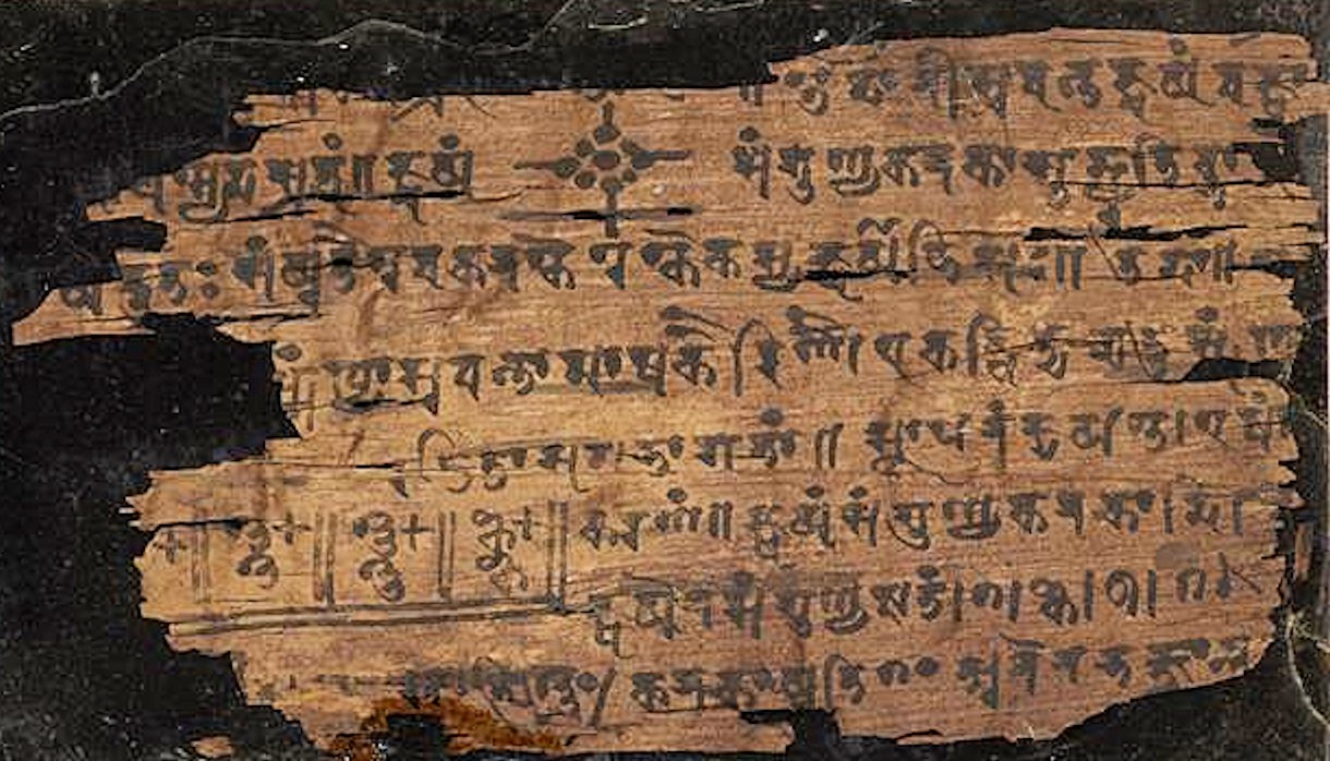 A birch-bark folio of the Bakhshali manuscript, its Sanskrit text and numerals faded and flaking.
