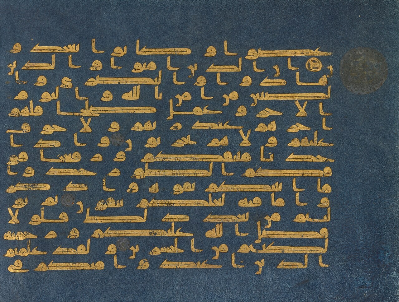 A folio of the Blue Qur'an, its Arabic verses written in gold Kufic script on deep blue vellum.