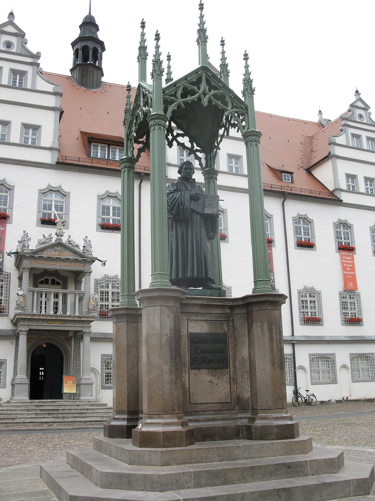 The Luther Monument in Wittenberg's market square: Luther standing under a Gothic canopy, the town's church towers behind.