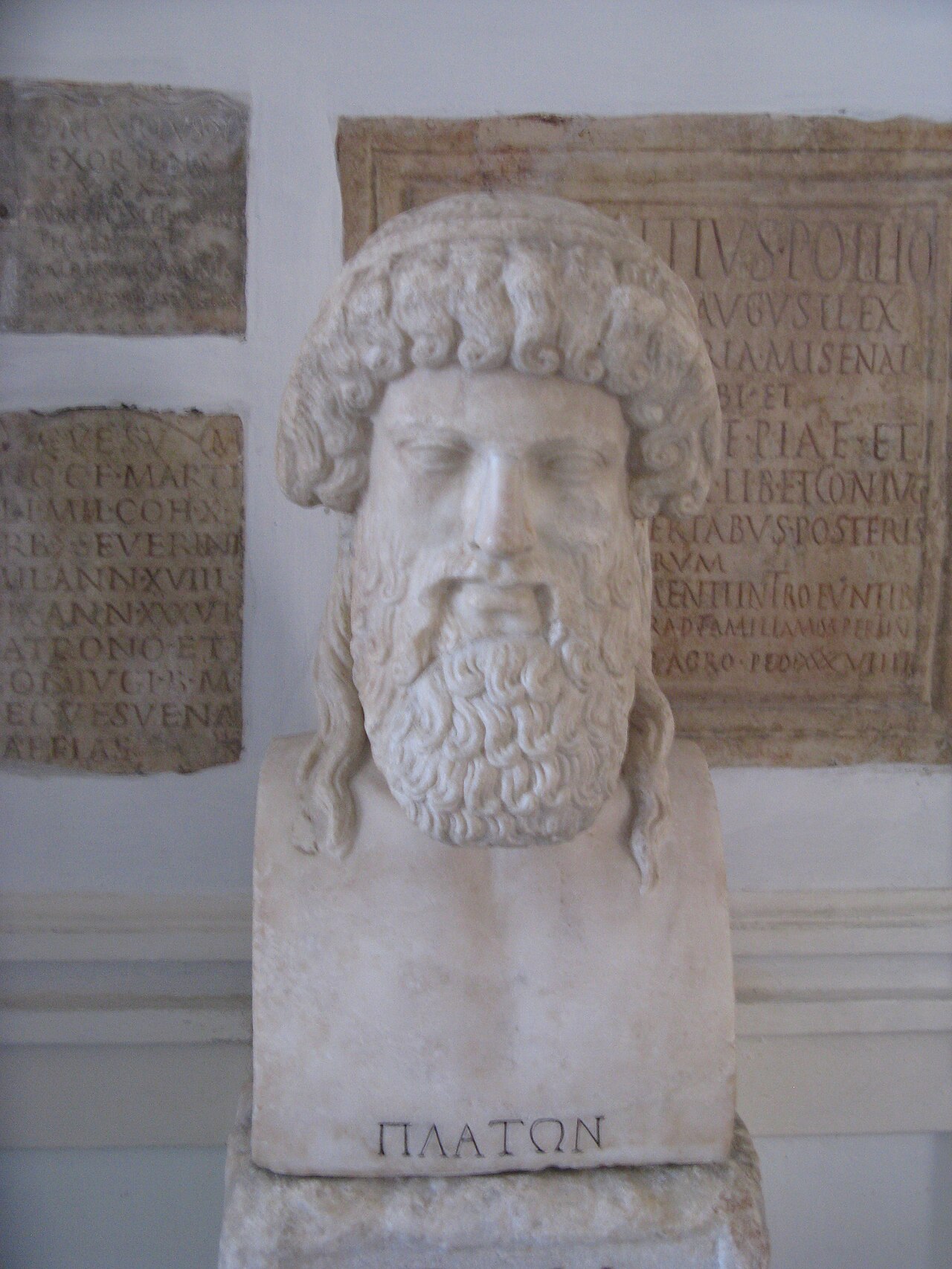 The marble herm of Plato in the Capitoline Museums, his name inscribed at its base, inscribed tablets on the wall behind.